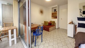 Un espace de vie compact comprenant un coin repas, un canapé, une petite table et un réfrigérateur.