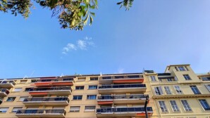 Un immeuble à plusieurs étages, doté de balcons, d’une enseigne bien visible et surplombant un ciel d’un bleu éclatant.