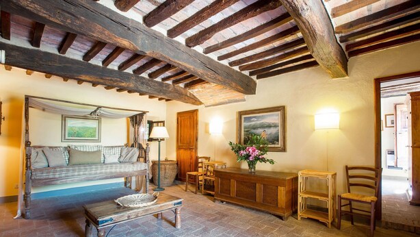 Una habitación rústica con vigas de madera a la vista, un sofá, una mesa de madera y un banco.
