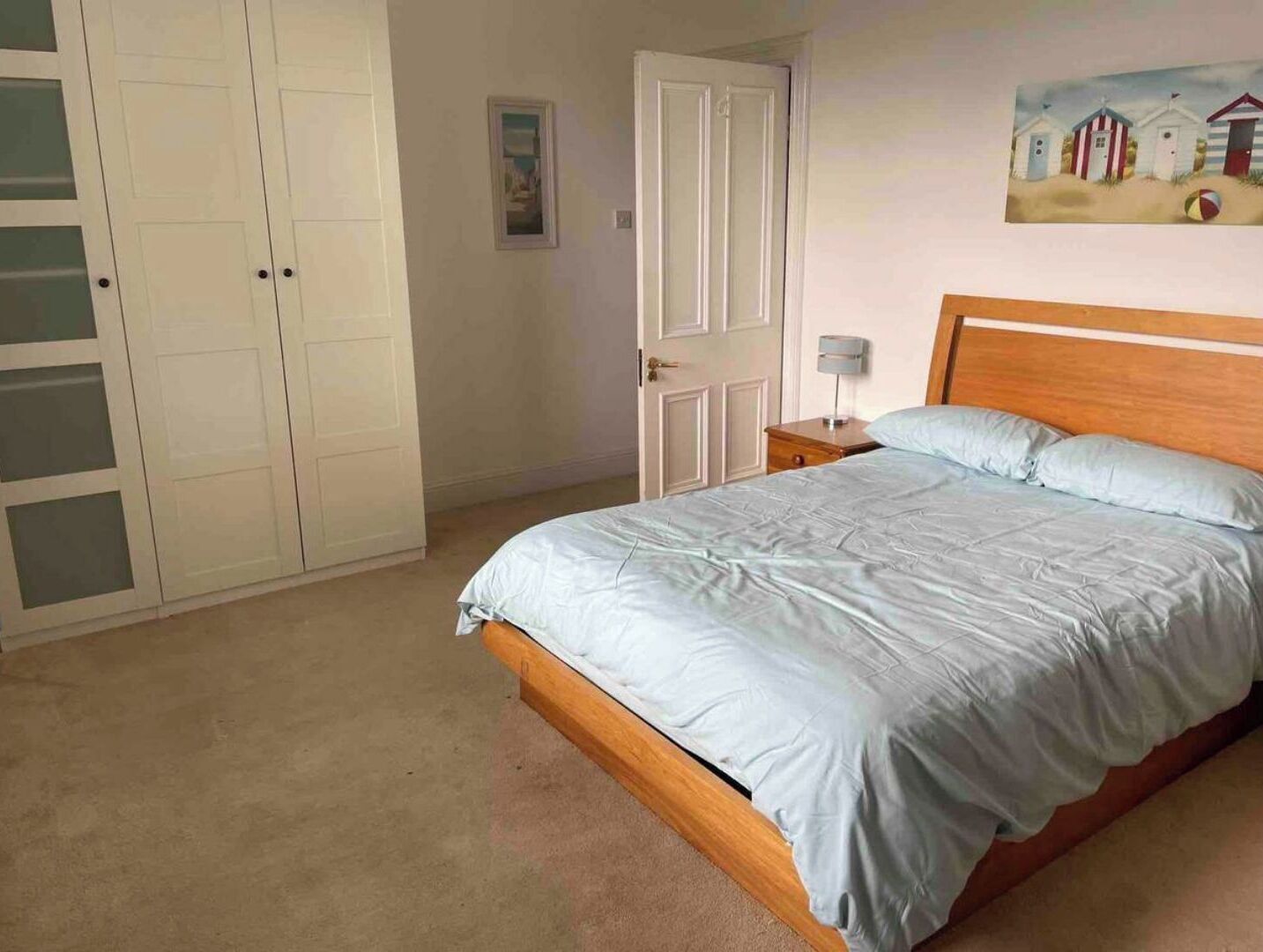 Ein Schlafzimmer mit Bett, Nachttisch, Kleiderschrank und einem Bild an der Wand.