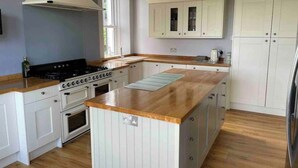 Une cuisine avec des armoires blanches, un plan de travail en bois, une cuisinière et un évier.