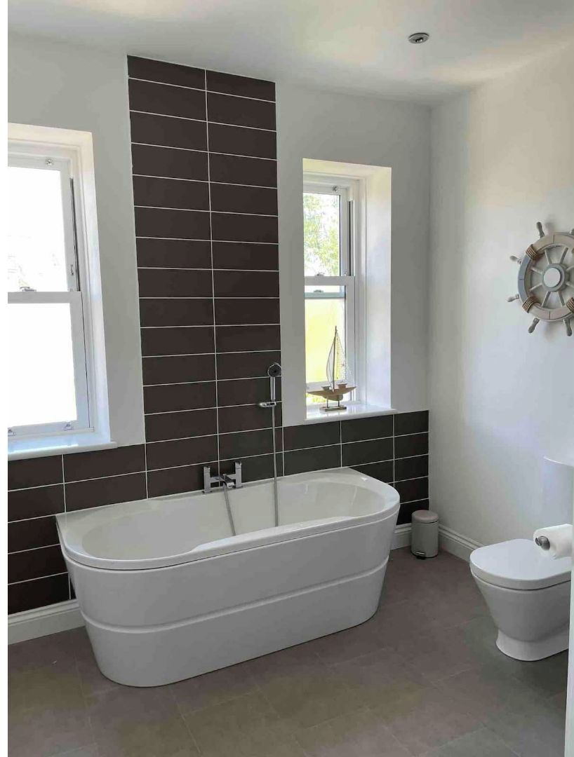Ein Badezimmer mit einer freistehenden Badewanne, einer Toilette und einer Schiffslenken-Dekoration an der Wand.