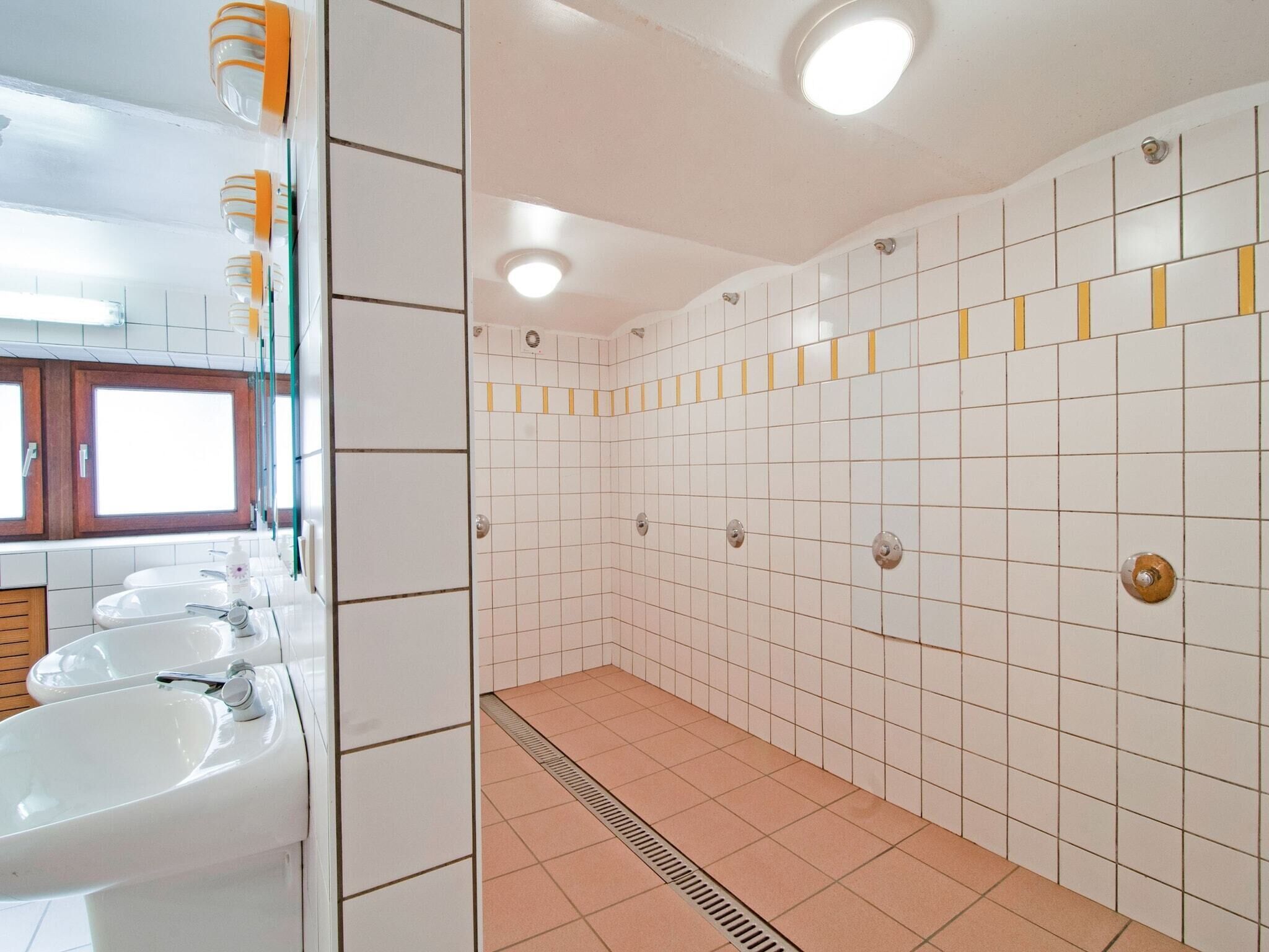 A bathroom with white tiled walls, a tiled floor, and a window above the sink.
