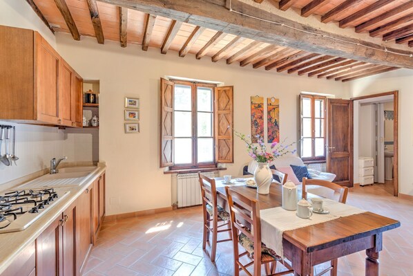 A kitchen with wooden cabinets, a gas stove, and a dining area with a table and chairs.