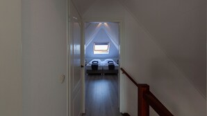 A narrow hallway leading to a bedroom with a skylight.