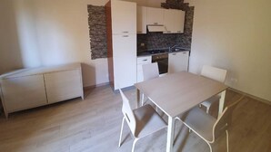 Una cocina compacta con armarios blancos, estufa integrada y protector contra salpicaduras de piedra.