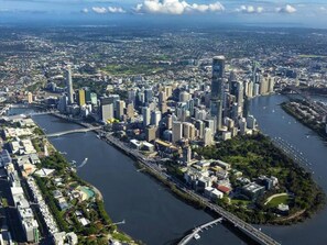 Paisagem urbana com um rio proeminente serpenteando pela cidade, cercada por edifícios altos.