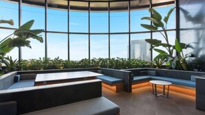A modern lounge area with curved seating, large windows, and indoor plants. - 2BR Luxury Skytower CBD Pool Gym Netflix (Brisbane)