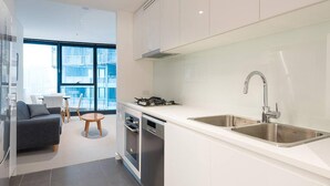 A modern kitchen with white cabinets, a stainless steel sink, and a gas stove. - 2BR Luxury Skytower CBD Pool Gym Netflix (Brisbane)