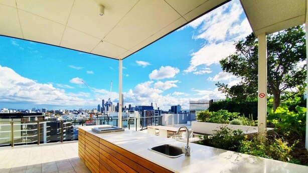 Une terrasse sur le toit avec une cuisine moderne, une vue sur la ville et un panneau indiquant qu'il est interdit de fumer.