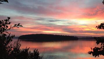 Un lac paisible au coucher du soleil, avec la silhouette d’une île qui se dessine à l’horizon.