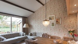 A modern living room with a large wooden dining table, comfortable seating, and a view of the outdoors. - Nice vacation home in Horssen with garden (Horssen)