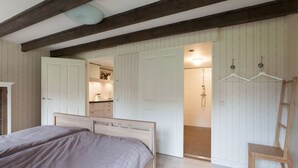A bedroom with two beds, a wooden ceiling, and a bathroom visible through an open door. - Nice vacation home in Horssen with garden (Horssen)