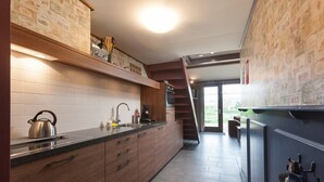A modern kitchen with wooden cabinets, a stainless steel kettle, and a built-in oven. - Nice vacation home in Horssen with garden (Horssen)