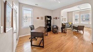 A spacious living room with a wooden dining table, a gray sofa, and a bookshelf. - Classic Lincoln Park  2 bedroom condo- parking included (Chicago)