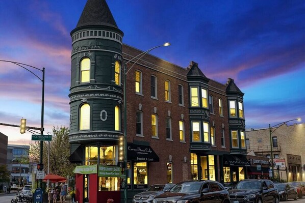 A historic building with a tower, multiple storefronts, and parked cars. - Classic Lincoln Park 2 bedroom condo- parking included (Chicago)