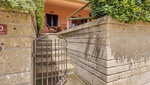Un muro in pietra con un cancello in metallo che dà accesso a un ingresso.