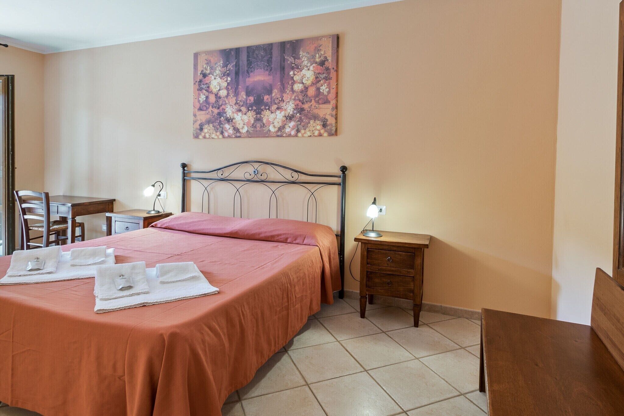 A hotel room with a bed, bedside tables, a desk, and a chair.