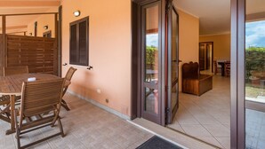 Un tavolo da pranzo in legno con sedie, una porta scorrevole in vetro che dà su un balcone e vista sull'esterno.