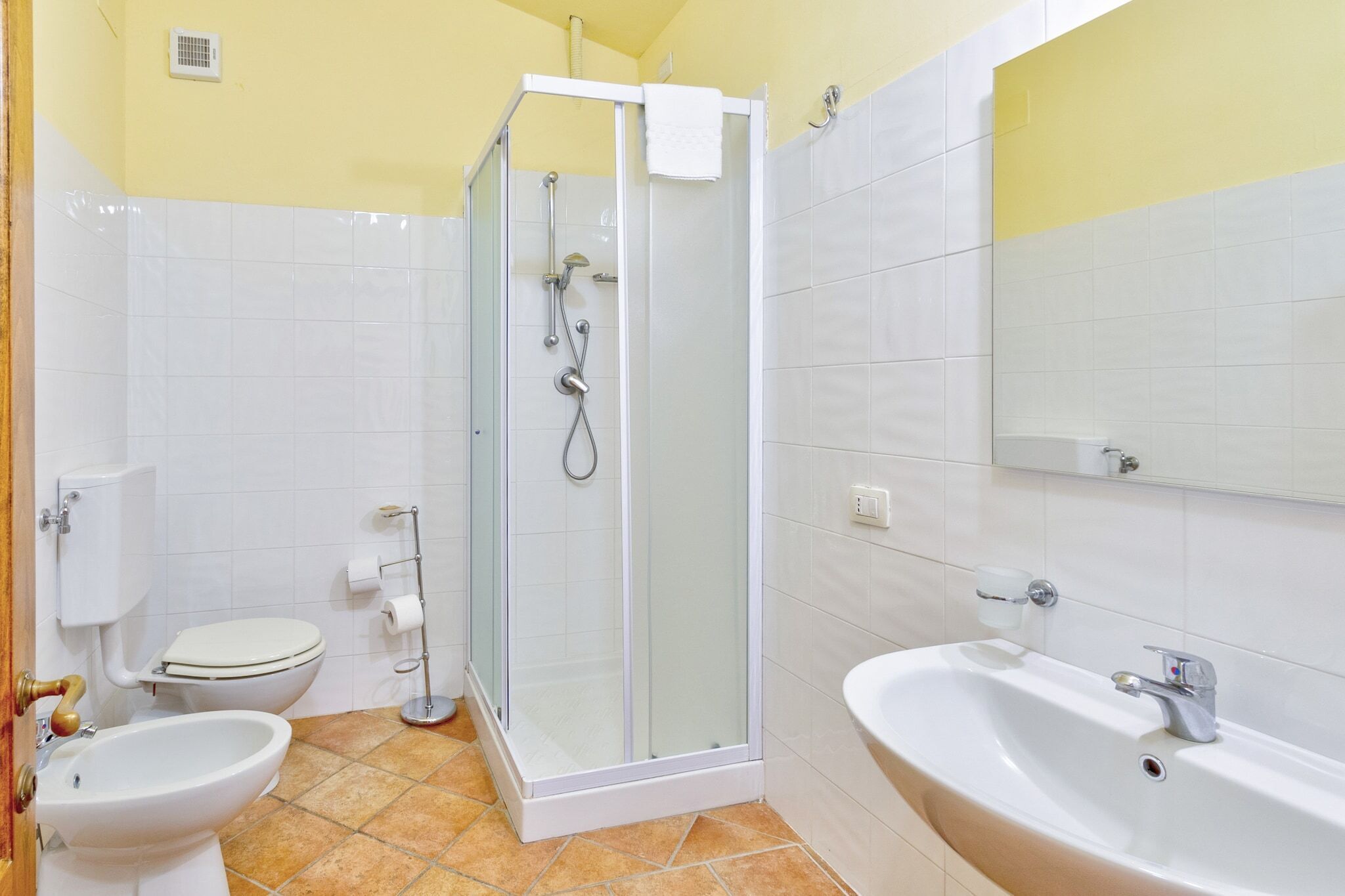 A bathroom with a toilet, bidet, shower, and sink.