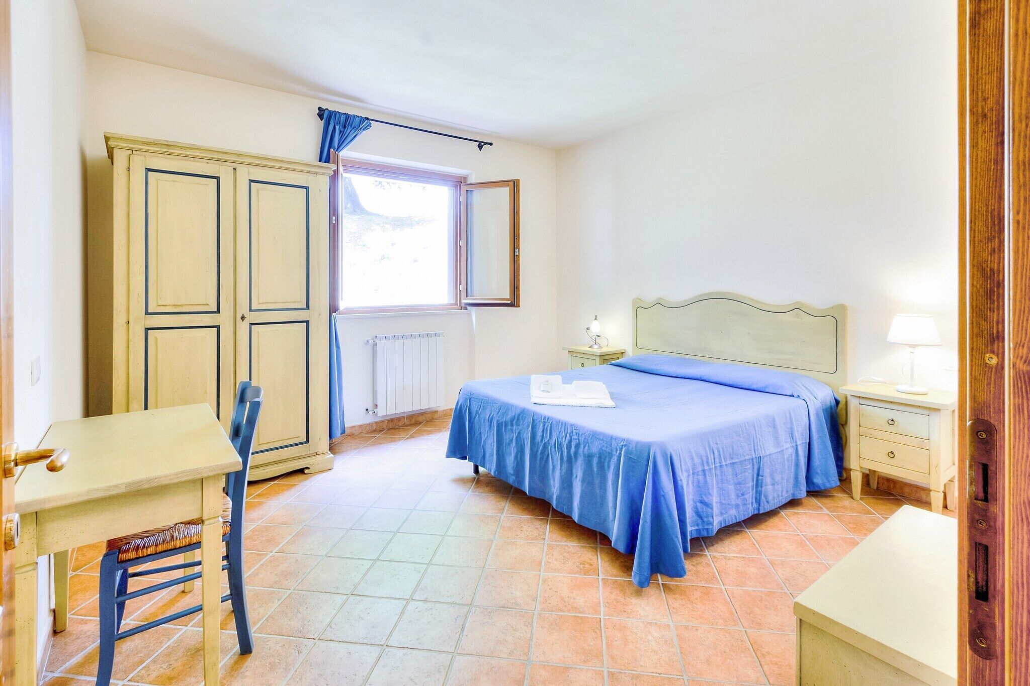 Une chambre à coucher comprenant un lit, un bureau, une chaise, une armoire et une fenêtre.