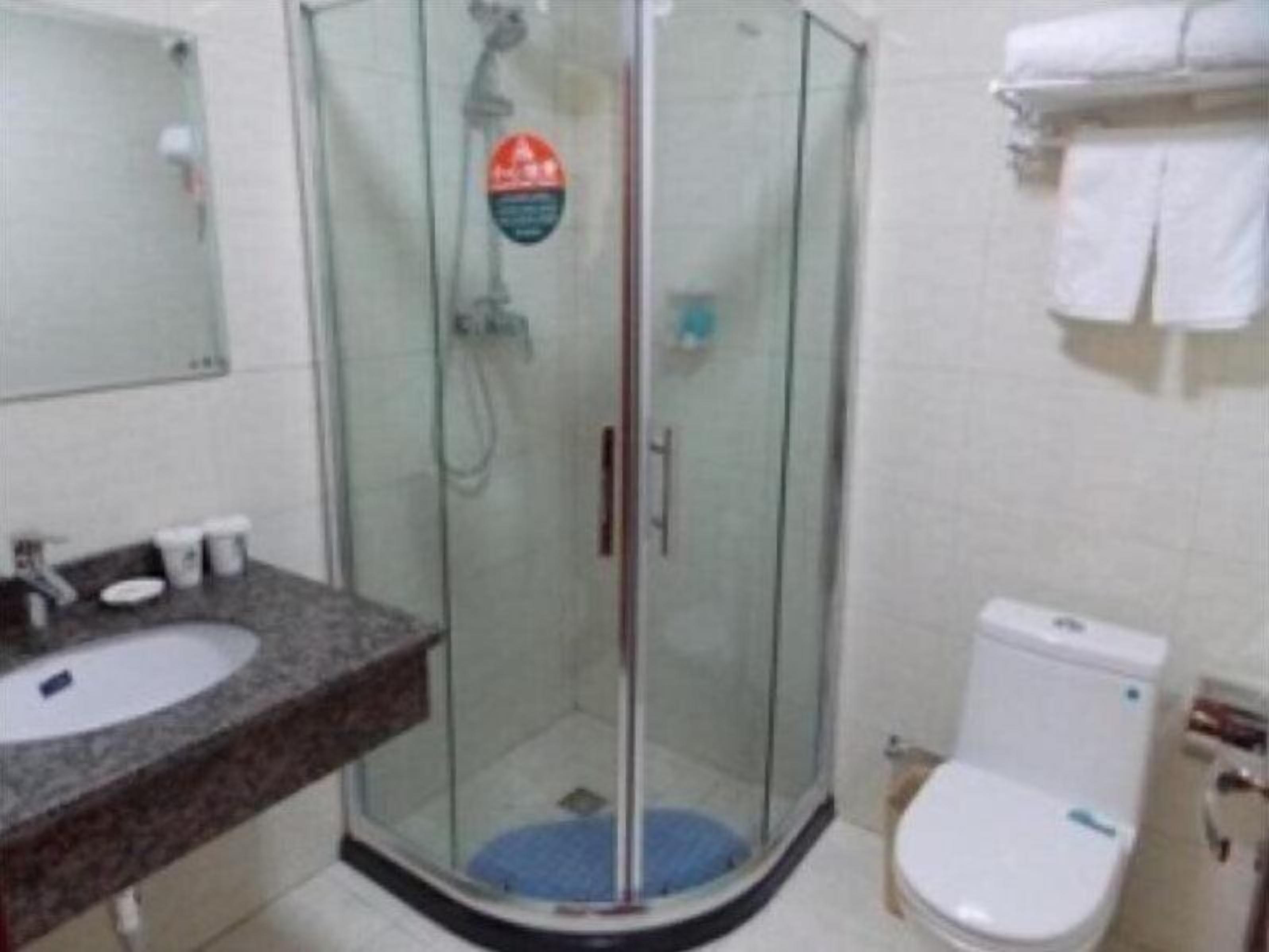 A bathroom with a glass-enclosed shower, a sink, and a toilet.
