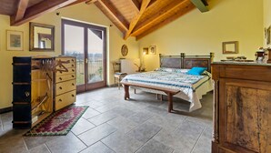 A bedroom with a wooden ceiling, a bed with a blue pillow, a dresser, and a radiator. - Belvilla by OYO Secluded Apartment with Balcony (Romagnano Sesia)