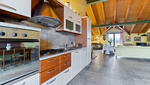 A kitchen with a stove, oven, microwave, and cabinets. There is a dining table with chairs and a window in the background. - Belvilla by OYO Secluded Apartment with Balcony (Romagnano Sesia)