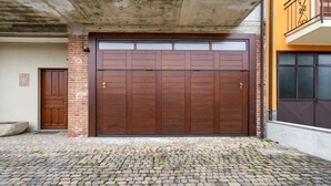 A large wooden garage door with a brick wall and a concrete overhang. - Belvilla by OYO Secluded Apartment with Balcony (Romagnano Sesia)
