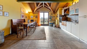 A kitchen with a wooden ceiling, tiled floor, and a dining area with a table and chairs. - Belvilla by OYO Secluded Apartment with Balcony (Romagnano Sesia)