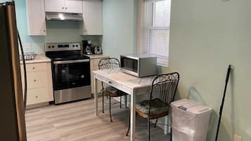 Une cuisine compacte équipée d’une cuisinière, d’un four à micro-ondes et d’une table à manger avec des chaises.
