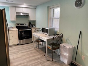 Une cuisine compacte équipée d’une cuisinière, d’un four à micro-ondes et d’une table à manger avec des chaises.