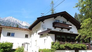 A two-story building with a balcony, a satellite dish, and a mountain backdrop. - Apartment in Scheffaui near Ski Slopes (Scheffau am Wilden Kaiser)