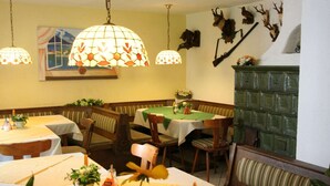 A cozy restaurant interior with wooden booths, hanging lamps, and a fireplace. - Apartment in Scheffaui near Ski Slopes (Scheffau am Wilden Kaiser)