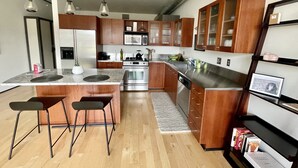 Une cuisine moderne avec des meubles en bois, des appareils électroménagers en acier inoxydable et des luminaires suspendus.