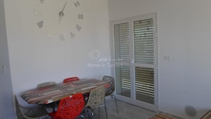 Ein Essbereich mit einer Uhr, einem Tisch, Stühlen und einer Glastür mit Jalousien.