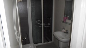 Ein Badezimmer mit Duschkabine aus Glas, Waschbecken und Spiegel.