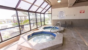 A spa area with two hot tubs, a view of the pool outside, and a sign indicating no throwing of objects in the pool.