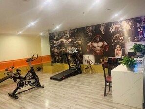 A gym with exercise equipment, a treadmill, and a wall with fitness-related artwork. - Shell Shanghai Songjiang District Xinqiao Town Xinqiao Hotel (Shanghai)