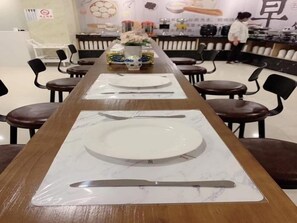 A dining area with a long table set for multiple people, chairs around the table, and a counter in the background. - Shell Shanghai Songjiang District Xinqiao Town Xinqiao Hotel (Shanghai)