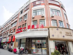 A hotel with a curved facade, multiple balconies, and a prominent entrance with a glass door. - Shell Shanghai Songjiang District Xinqiao Town Xinqiao Hotel (Shanghai)