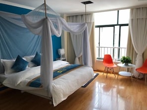 A bedroom with a bed, a canopy, a small table with a plant, and two chairs. - Shell Shanghai Songjiang District Xinqiao Town Xinqiao Hotel (Shanghai)