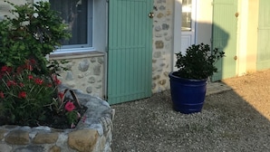 A stone building with a tiled roof, a green door, and a window. There is a large potted plant in front. - House with swimming pool in lavender fields near the Gorges du Verdon (Bras-d'Asse)