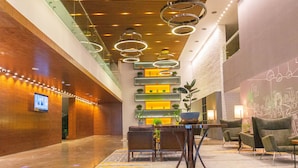 A modern lobby with a marble floor, a reception desk, and a seating area with chairs.