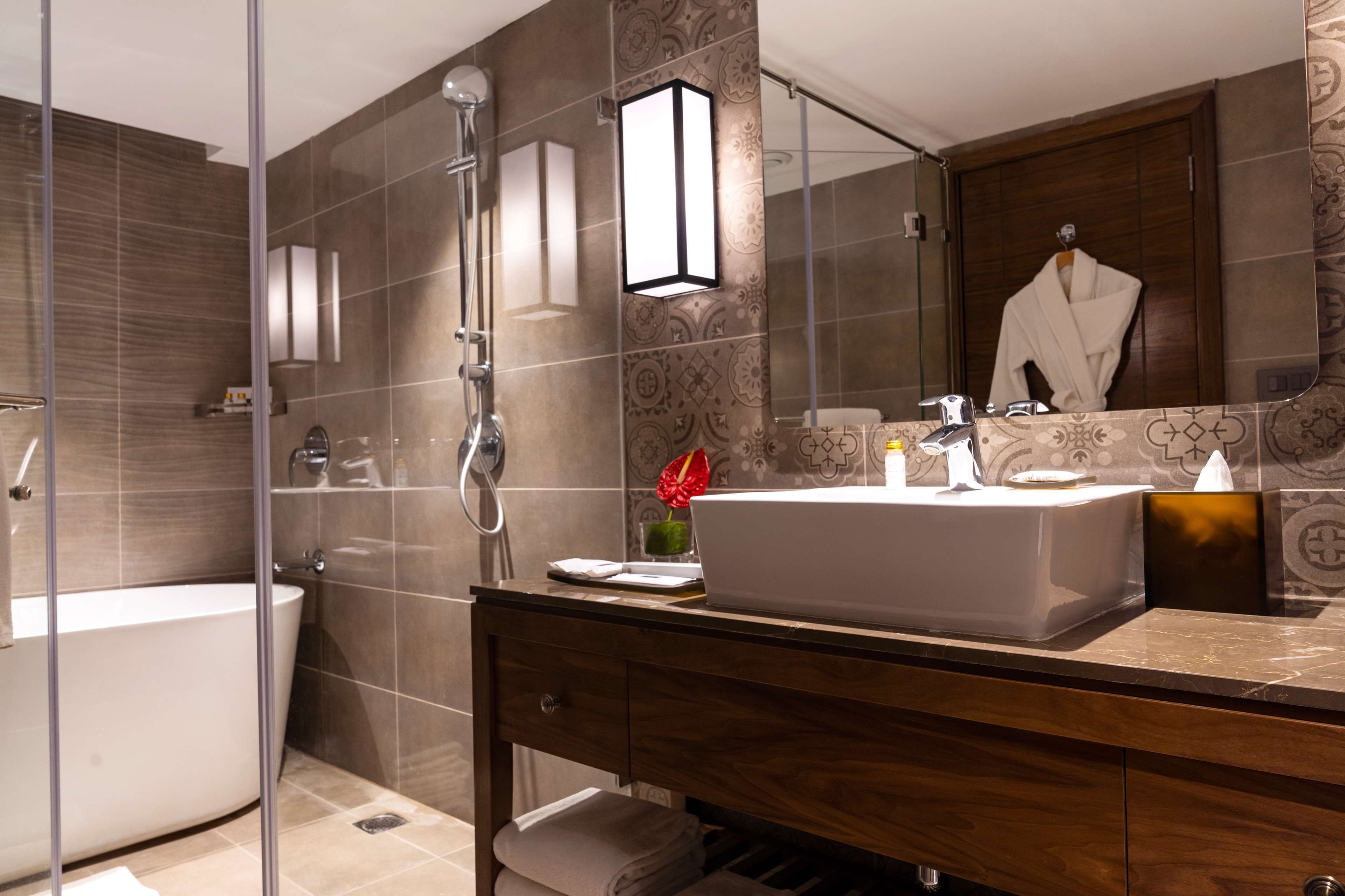 A modern bathroom with a glass-enclosed shower, a white sink, and a wooden vanity.