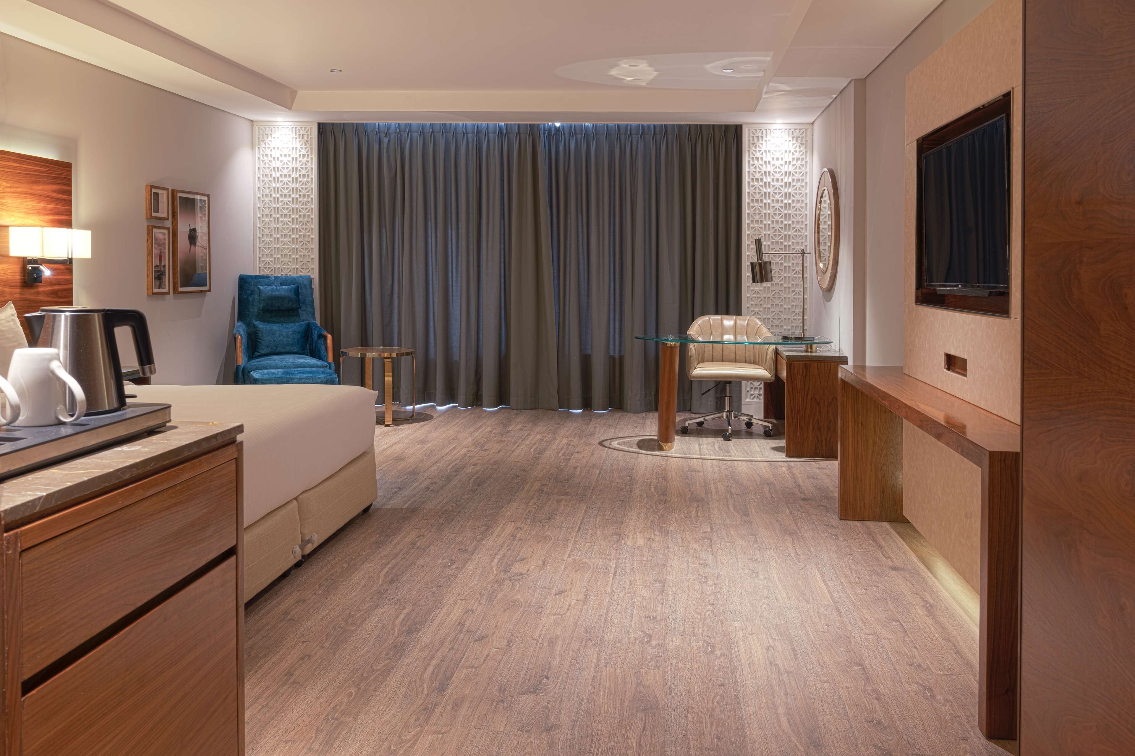Una habitación de hotel con cama, escritorio, silla, televisor y cafetera.