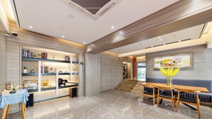 A modern hotel lobby with a reception desk, a seating area with a table and chairs, and a bookshelf filled with books and decorative items. - Fuman Renjia Hotel Xiamen Zhongshan Road (Xiamen)