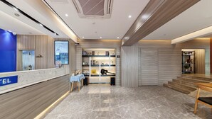 A hotel reception area with a digital display, a reception desk, and a seating area with a table and chairs. - Fuman Renjia Hotel Xiamen Zhongshan Road (Xiamen)