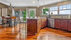 Une cuisine spacieuse avec des meubles en bois, un grand îlot central et un coin repas équipé de tabourets de bar.