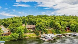 Une propriété au bord du lac comprenant plusieurs maisons, des bateaux amarrés et une végétation luxuriante.
